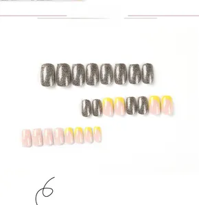 Detailed view of yellow French press-on nails with white daisy patterns and silver glitter