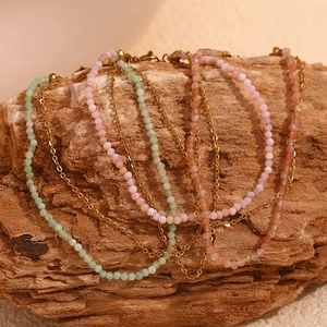 Detail of 18K gold-plated anklets with colorful natural stones on wooden base