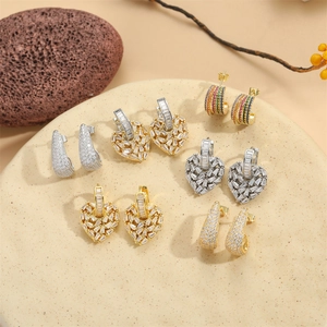 Collection of heart-shaped zircon earrings and gold hoops on an elegant stone display
