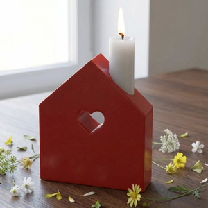 Cozy red house candle holder with heart cutout and lit candle on rustic wood