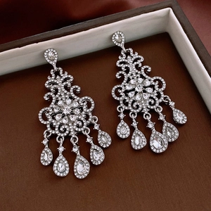 Detailed view of silver bow earrings with long tassels and sparkling zircon stones
