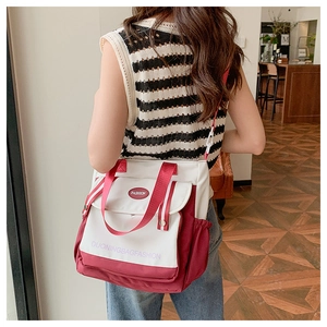 Detail of red and white canvas tote bag showing the side pocket and textile texture
