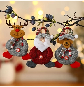 Detalle de adornos navideños de peluche con reno y Papá Noel colgados en un árbol