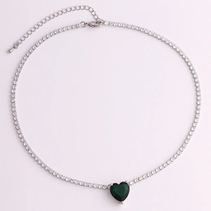 Detailed view of silver tennis chain necklace with a deep green heart-shaped zirconia pendant