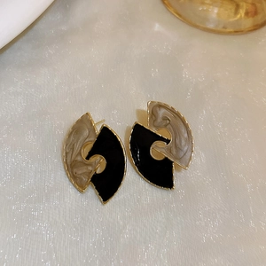 Detail of vintage gold-rimmed fan earrings with black and marble resin insets