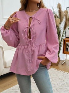 Detail of pink striped shirt featuring multi-tie front design and lantern sleeves