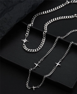 Detail of silver titanium star necklaces with cuban links on a black textured tray