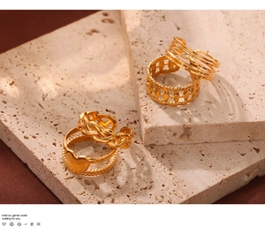 Detail view of gold-plated geometric ring set displayed on stone and brown fabric