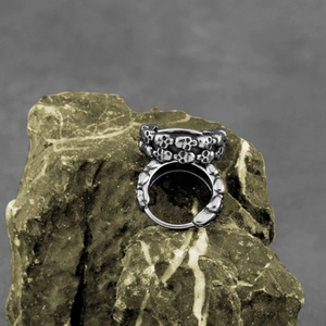 Gothic punk skull ring in silver metal finish displayed on a natural rock background