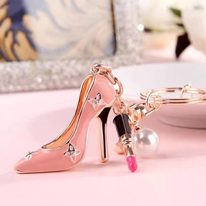 Detailed view of pink high heel keychain with lipstick charm and white pearl pendant