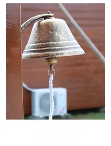 Detail of vintage cast iron door bell with antique bronze texture and white woven rope