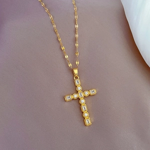 Detailed close-up of a gold titanium cross pendant set with sparkling zircon stones