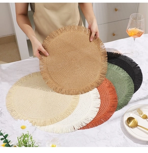 Dettaglio di tovagliette circolari intrecciate con frange in vari colori naturali