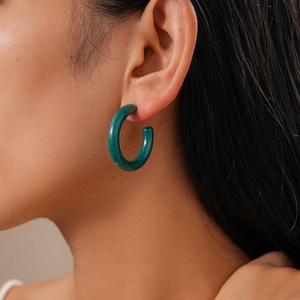 Close-up of a model wearing a glossy dark green acrylic C-shaped hoop earring