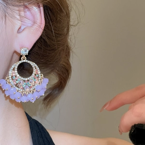 Close-up of geometric crystal tassel earrings with purple beads on a model wearing them