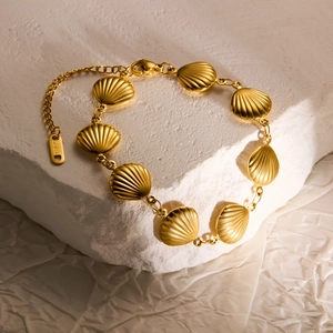 Golden titanium steel bracelet with shell charms on stone, minimalist marine style jewelry