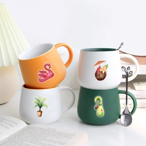Detail of stacked ceramic mugs featuring tropical flamingo and avocado cartoon prints
