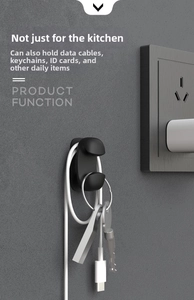 Macro detail of a black wall-mounted adhesive hook holding a charging cable and keys