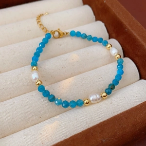 Detail of blue bead and pearl bracelet with gold lobster clasp on velvet jewelry box