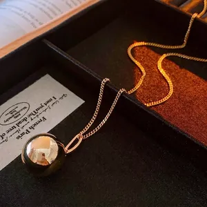 Minimalist gold sphere pendant necklace with polished mirror finish on dainty chain link