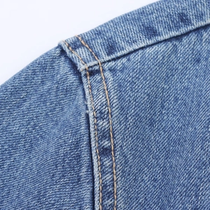 Detailed close-up of blue denim dress featuring orange contrast stitching and twill texture