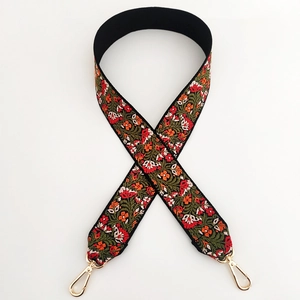 Detail of floral embroidery bag strap with orange and red flowers and gold metal hooks