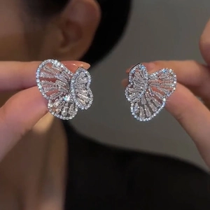Close-up of butterfly stud earrings with sparkling cubic zirconia on a model's ear