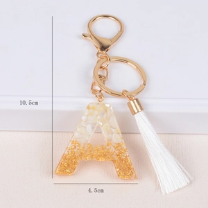 Detailed view of resin letter A keychain with gold foil and shell fragments plus white tassel