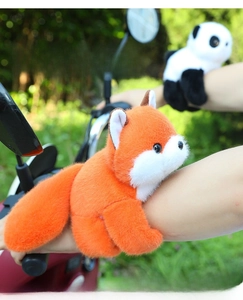 Close-up of fluffy panda and fox plush slap bracelets wrapped around a bike handle