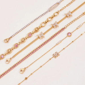 Detailed view of layered gold-plated stainless steel bracelets with pink and white zircons