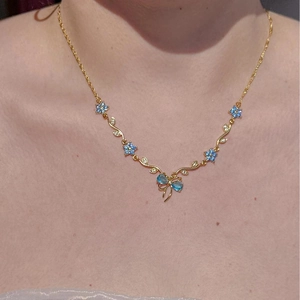 Detailansicht einer goldenen Pfirsichblütenkette mit blauen Kristallen am DamenHals