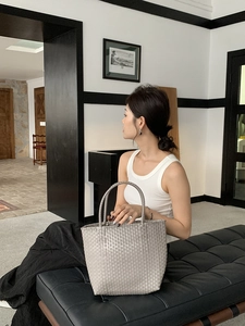 Close-up of grey woven tote bag texture with top handle in a minimalist indoor setting