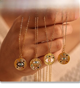 Gros plan de pendentifs œil maléfique colorés avec strass étincelants et finition PVD dorée