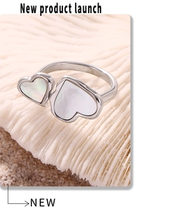 Macro detail of silver heart ring with natural white shell inlay on a seashell