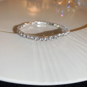 Gros plan d'un bracelet élastique en strass sur une assiette en porcelaine texturée blanche