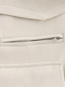 Détail macro du tissu texturé crème avec fermeture éclair en métal argenté et coutures fines