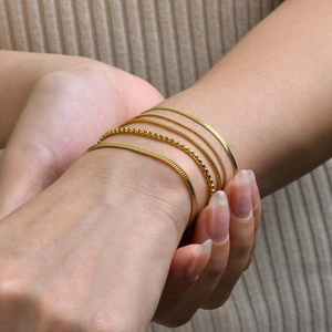 Detailed view of a 5-piece minimalist gold snake and bead chain bracelet set on wrist