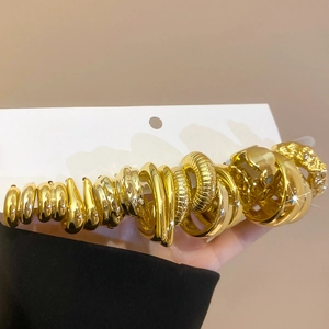 Detailed macro view showing a set of gold earrings with various polished and wrinkled textures