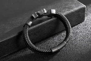Macro detail of men's braided black leather bracelet with brushed steel magnetic clasp