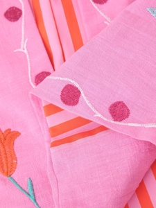 Close-up of pink cotton linen fabric with floral embroidery and striped lining detail