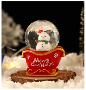 Detail of a Christmas snowman snow globe with red sleigh base and Merry Christmas text