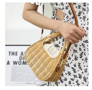 Detail of woven straw handbag featuring brown leather strap and white drawstring inner pouch