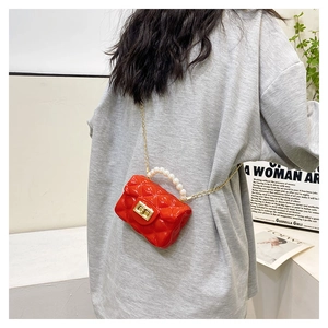 Detail showing the red quilted mini jelly bag with pearl handle worn over a grey coat