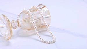 Close-up of natural freshwater pearl necklace draped over an amber glass cup for display