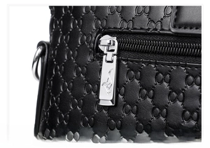 Close-up of silver metal zipper with kangaroo logo on black embossed leather bag