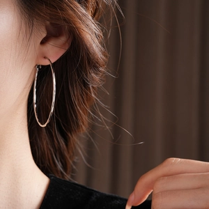 Détail de boucles d'oreilles créoles argentées avec fini martelé sur un mannequin