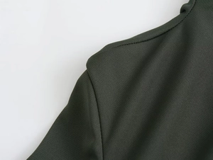 Detailed macro shot of the shoulder seam and texture on a dark green pleated midi dress