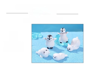 Detail view of miniature polar bear, penguin and seal resin figurines on blue sand