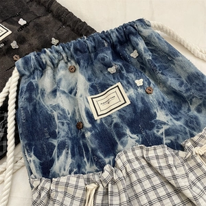 Detail von blauem Batik-Denim mit karierten Rüschen und weißem Schmetterlingsanhänger