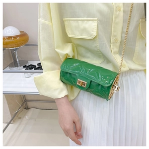 Detail of green quilted barrel crossbody bag with gold chain strap and pearl accent
